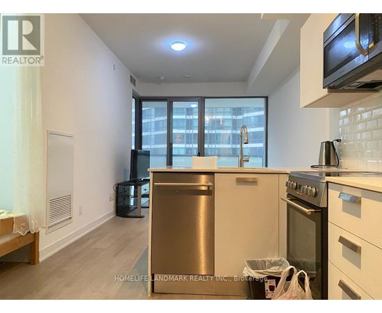 A kitchen with a stainless steel dishwasher and oven, and a window with a view of a cityscape.