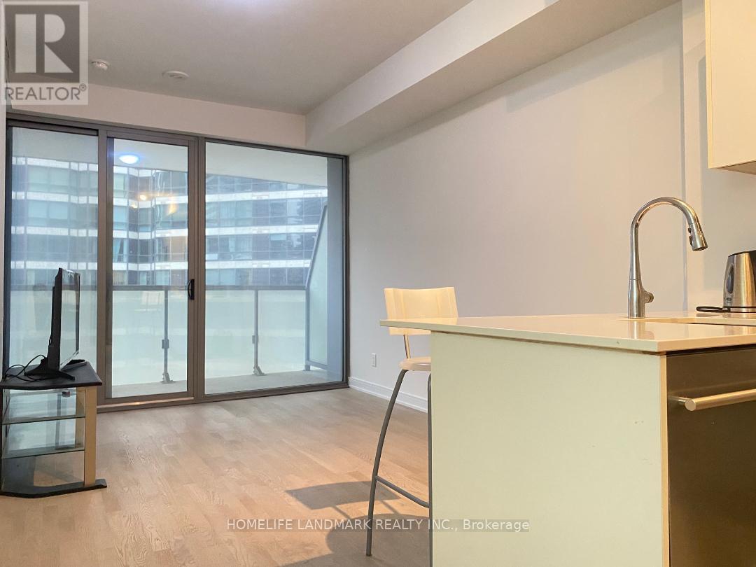 A kitchen with a sink, a chair and a window with a view of a city.