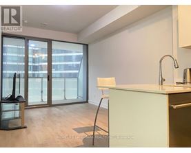 A kitchen with a sink, a chair and a window with a view of a city.