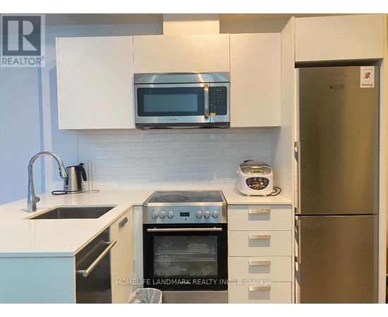 A kitchen with a stainless steel refrigerator and white cabinets.