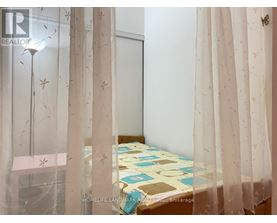 A bedroom with a bed covered in a patterned bedspread and curtains with a butterfly design.