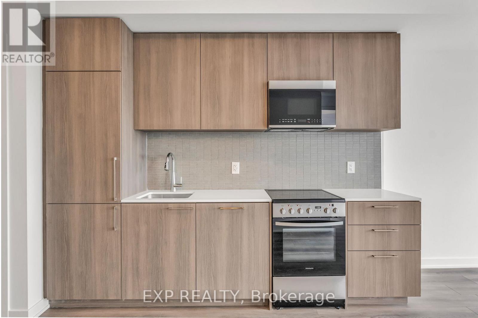 A kitchen with wooden cabinets and a microwave above the sink.