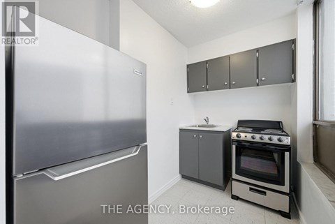 A small kitchen with a refrigerator, oven, and cabinets.