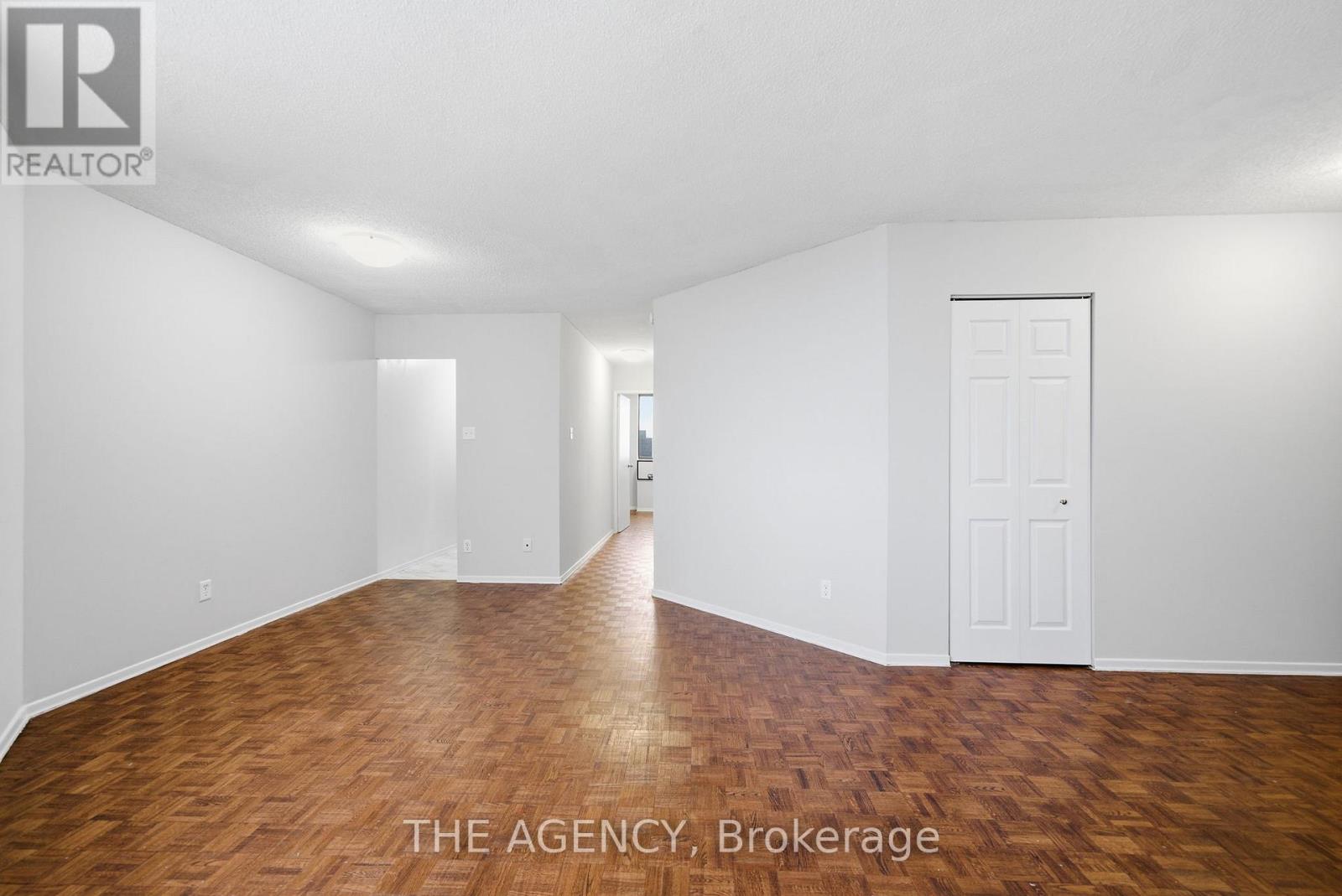 A room with wooden flooring and white walls, with a door on the right side.