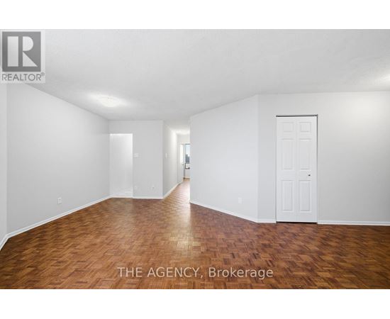 A room with wooden flooring and white walls, with a door on the right side.