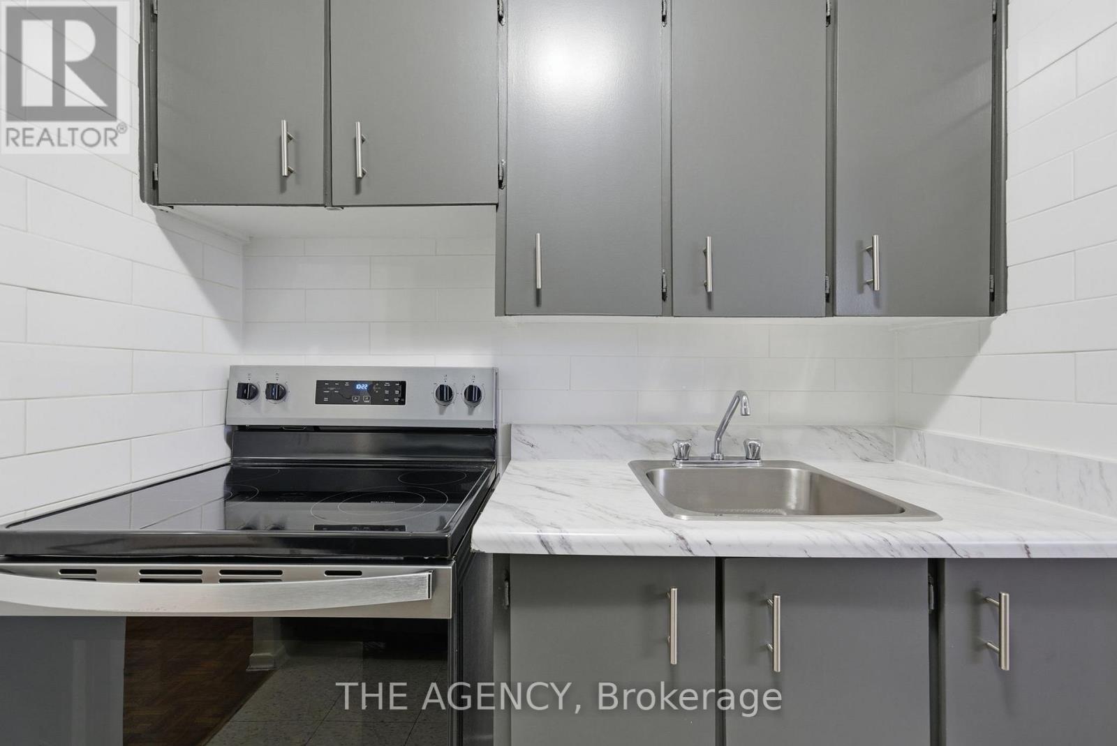 A kitchen with a stove, sink and cabinets.