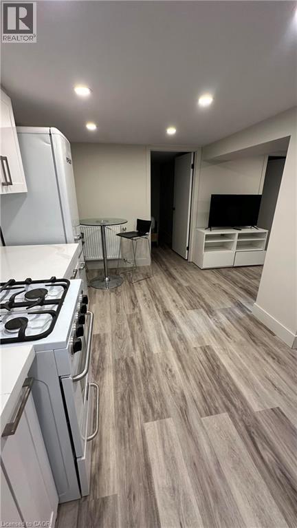 A modern kitchen with a wooden floor and white cabinets.