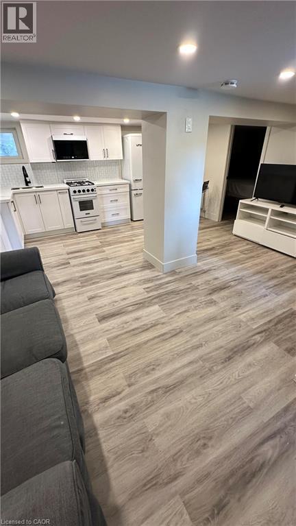 A modern kitchen with white cabinets and a grey sofa.