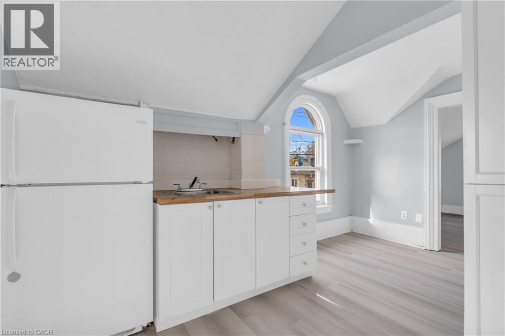 A white kitchen with a refrigerator, sink, and cabinets.