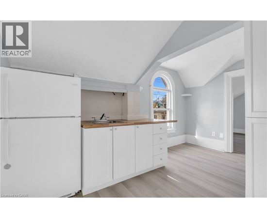 A white kitchen with a refrigerator, sink, and cabinets.