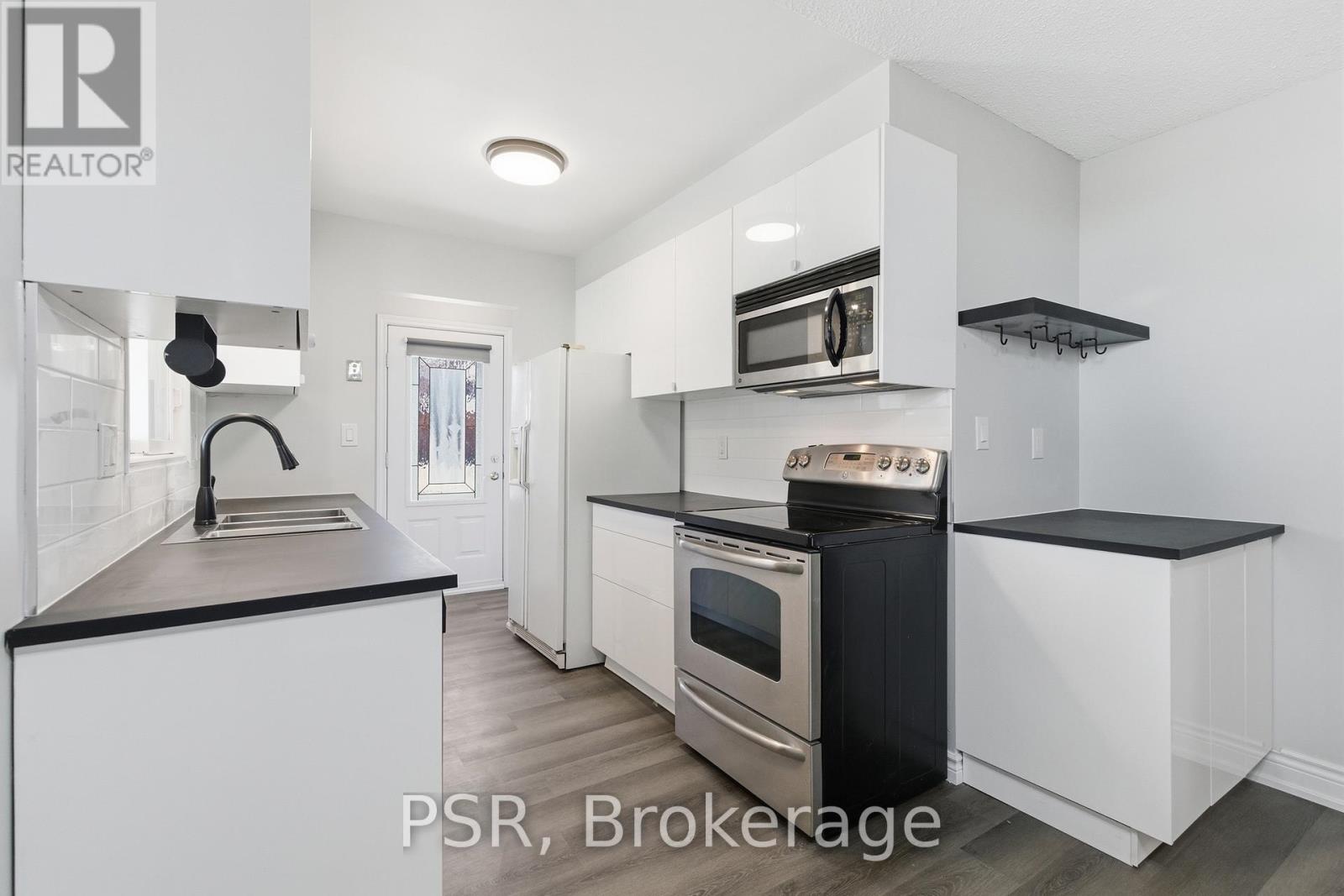 A modern kitchen with white cabinets and black countertops.