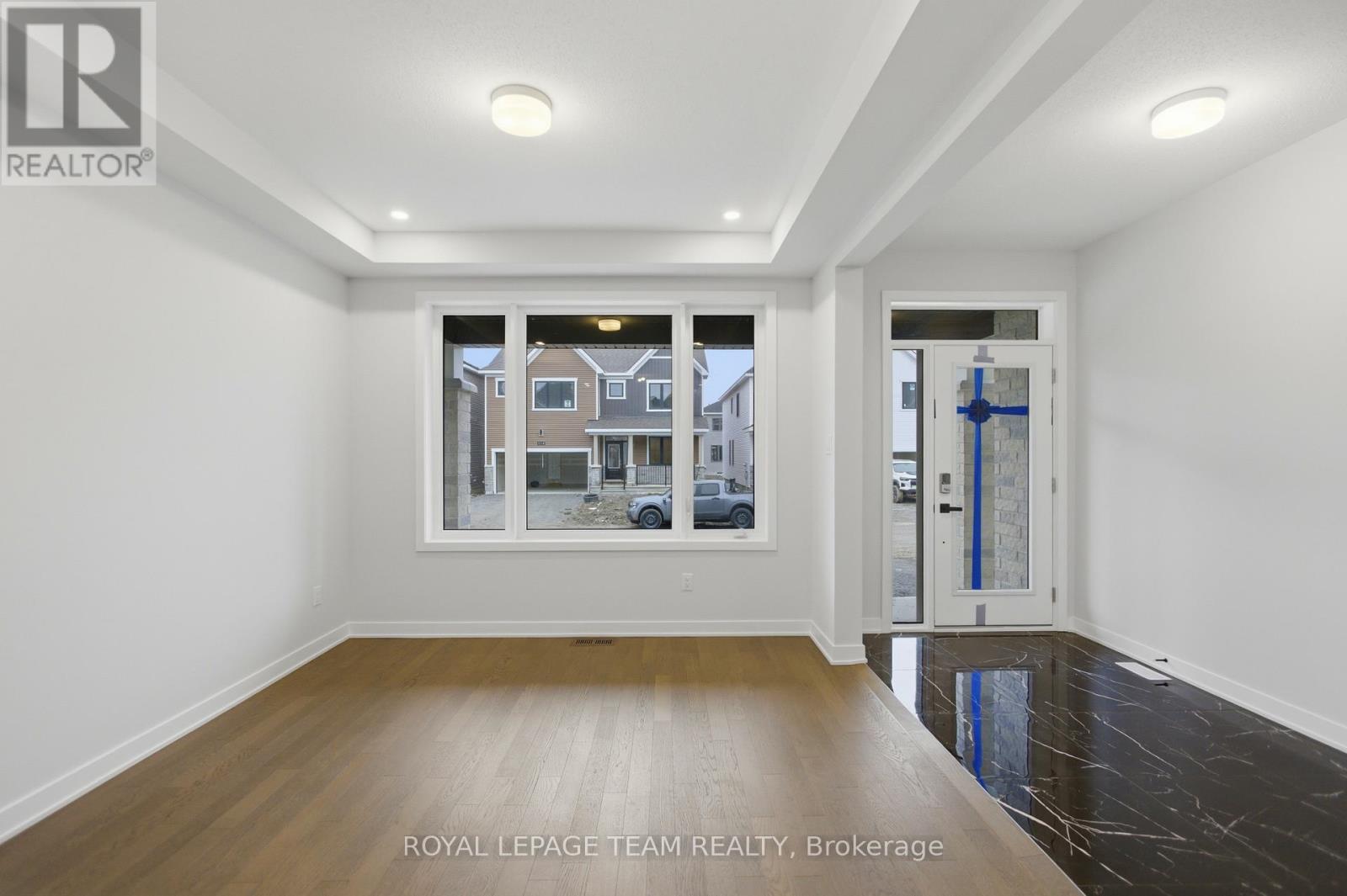 A white room with a window showing a view of a house and a blue ribbon.