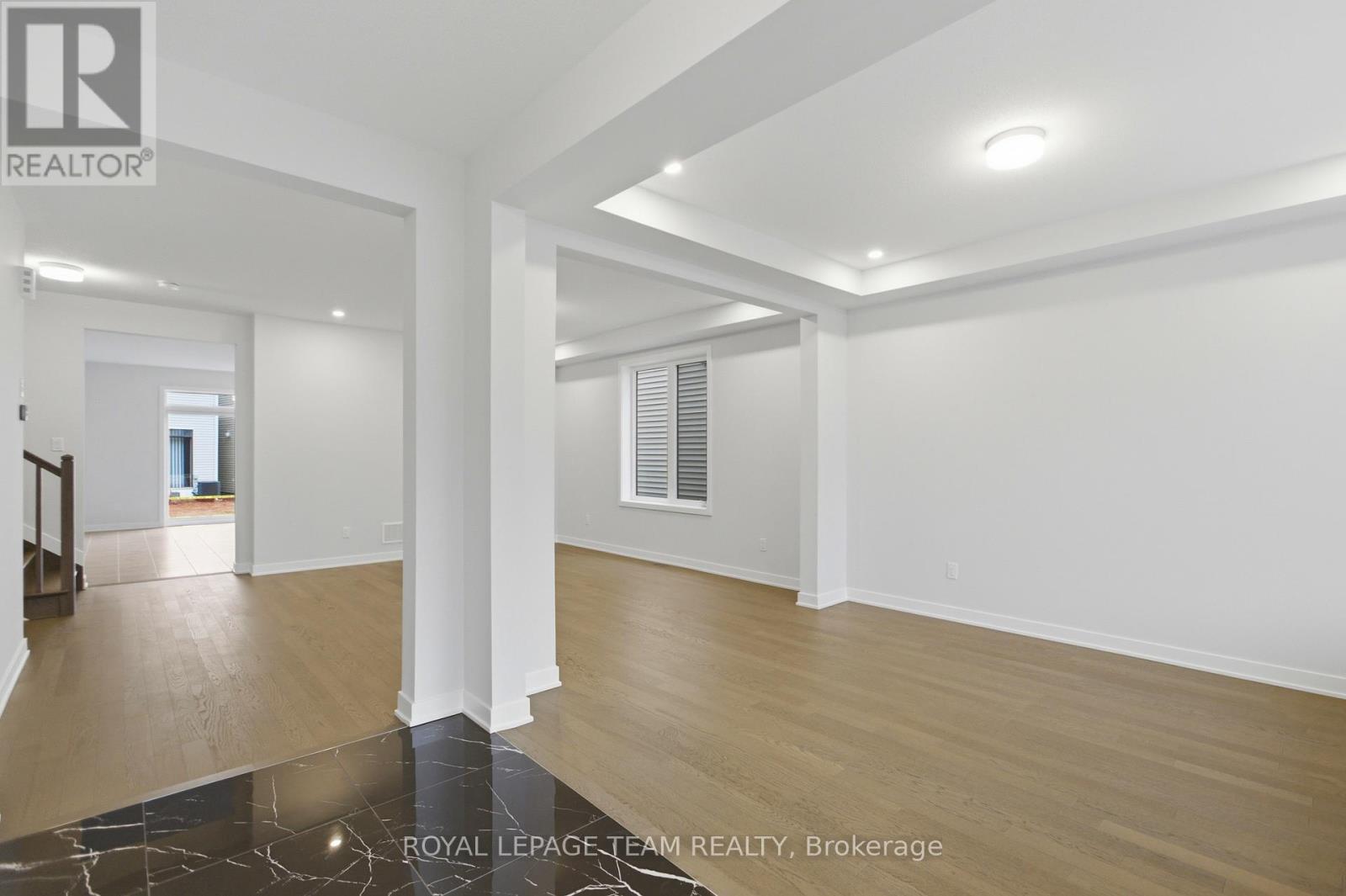 A spacious room with wooden flooring and white walls.