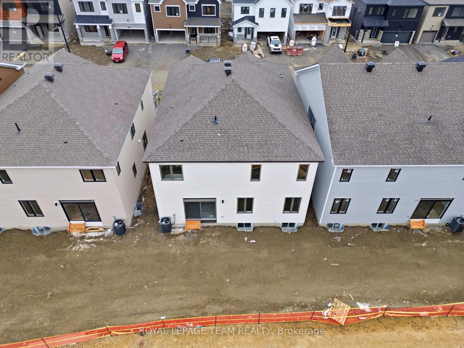 A construction site with a building under construction and a red car parked in the background.