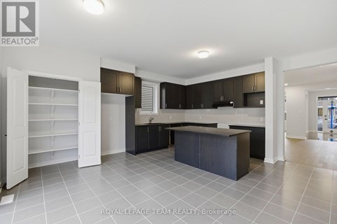 A spacious kitchen with dark brown cabinets and a central island.