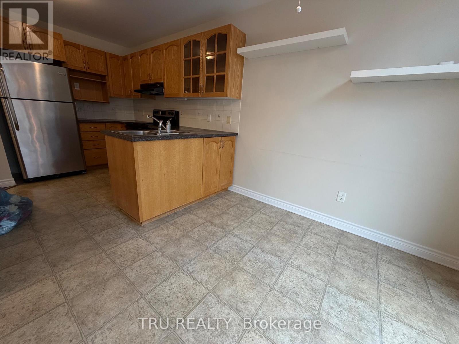 A kitchen with wooden cabinets and a tiled floor.