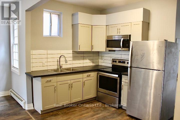 A kitchen with a stainless steel refrigerator and a black countertop.