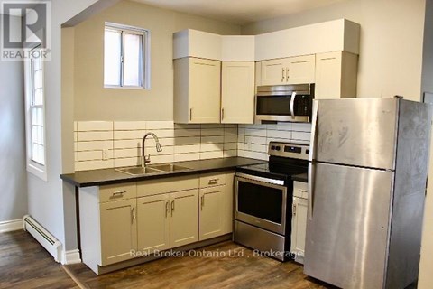A kitchen with a stainless steel refrigerator and a black countertop.