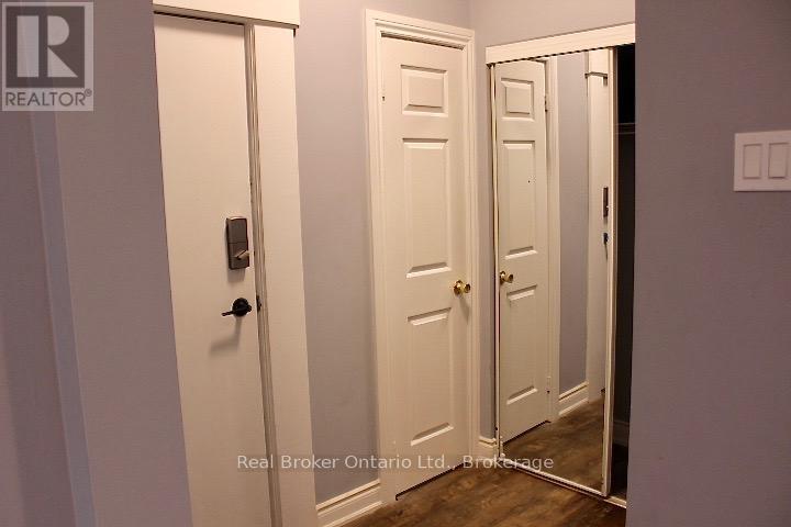 A hallway with two doors and a Real Broker logo.