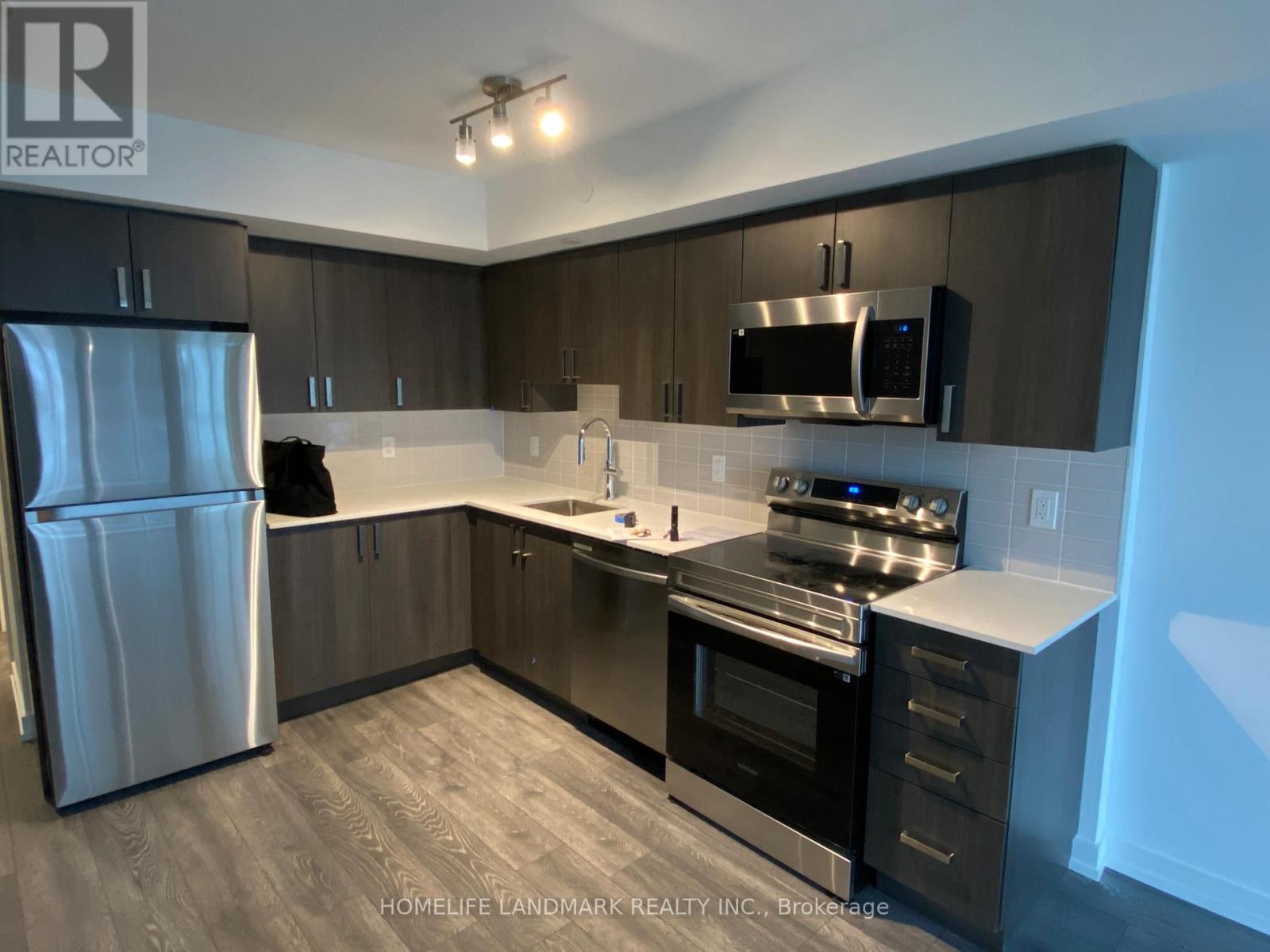 A modern kitchen with a stainless steel refrigerator and oven.