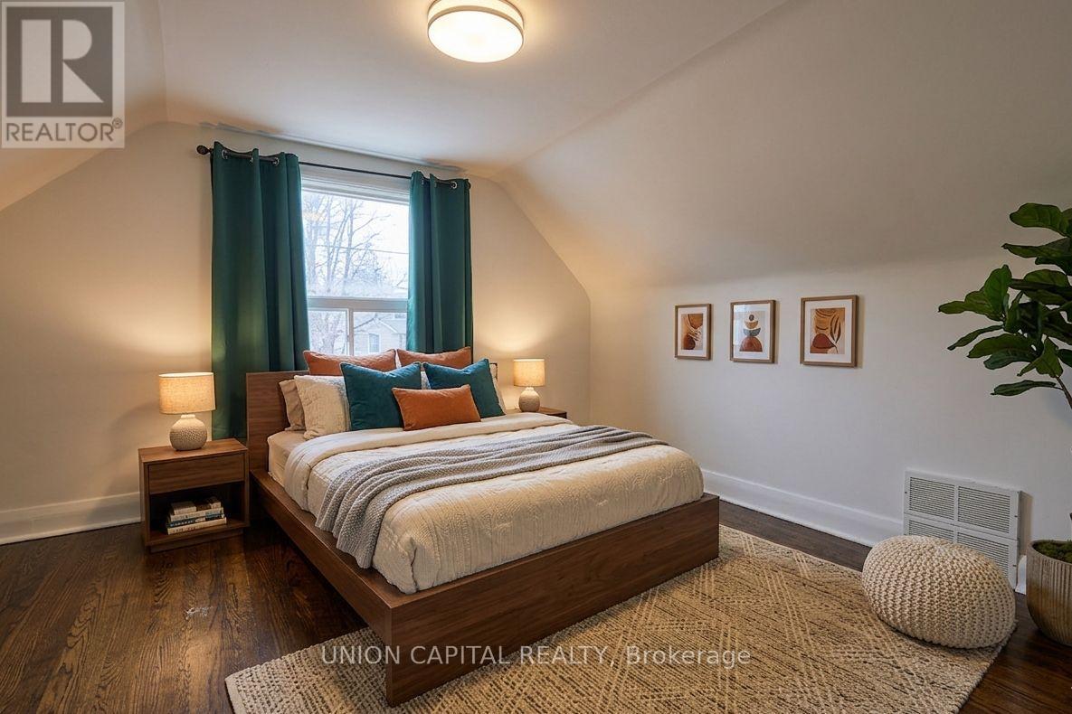 A bedroom with a large bed and a window with green curtains.