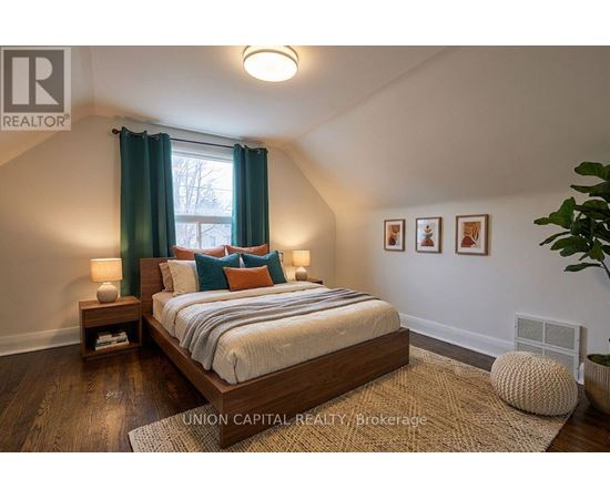 A bedroom with a large bed and a window with green curtains.