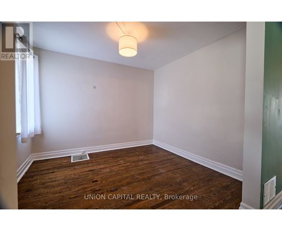 A room with wood flooring and white walls, with a light fixture hanging from the ceiling.