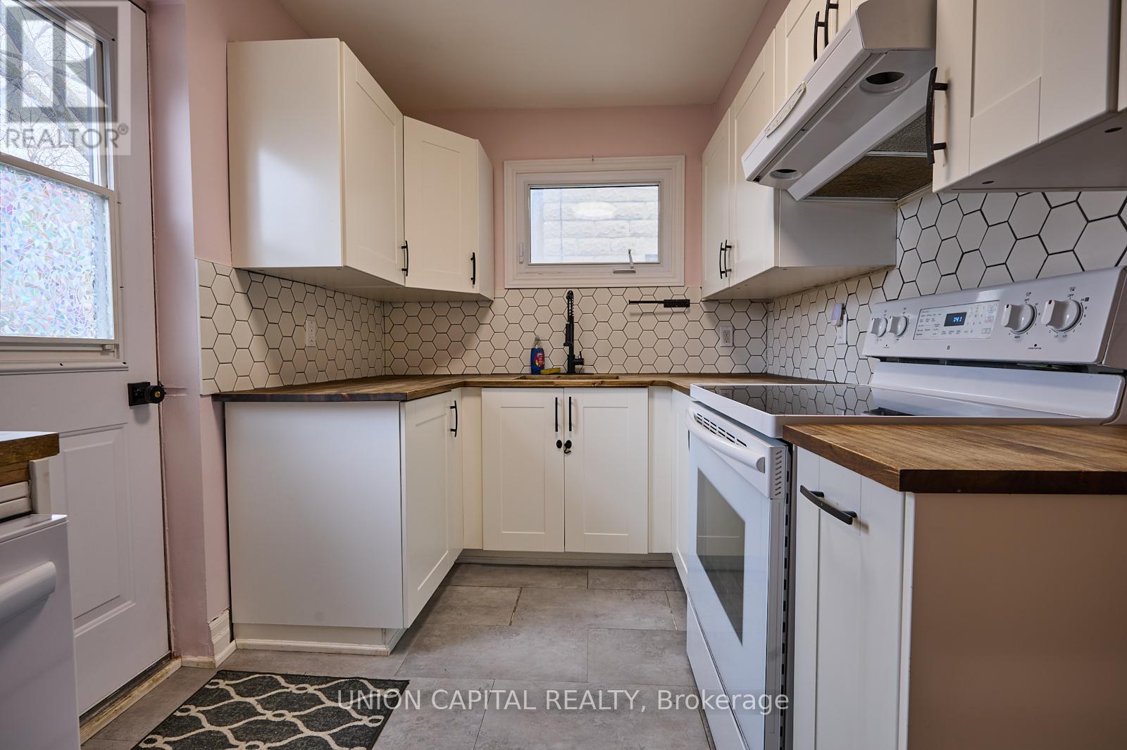 A kitchen with white cabinets and a black and white tile backsplash.