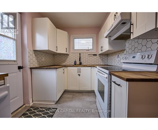 A kitchen with white cabinets and a black and white tile backsplash.