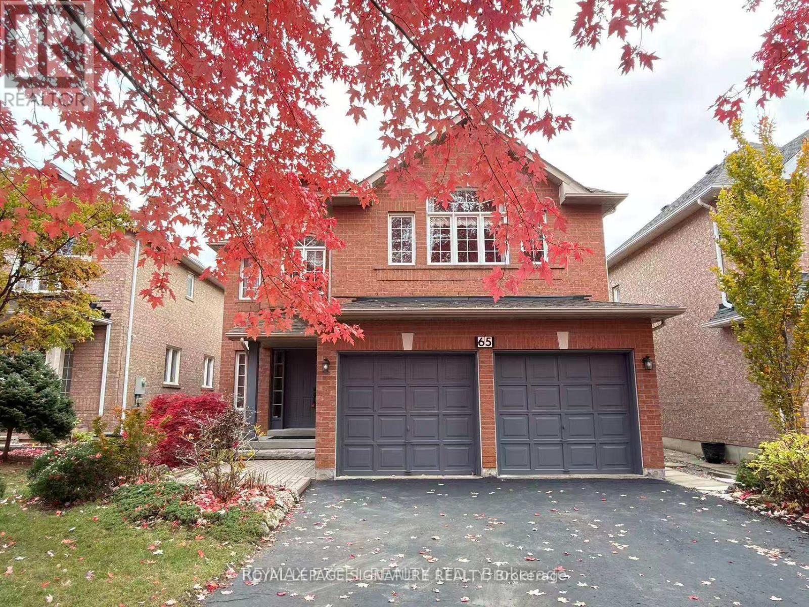 A house with a grey garage door is surrounded by trees with red leaves.