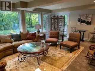 A living room with a glass table and brown chairs.