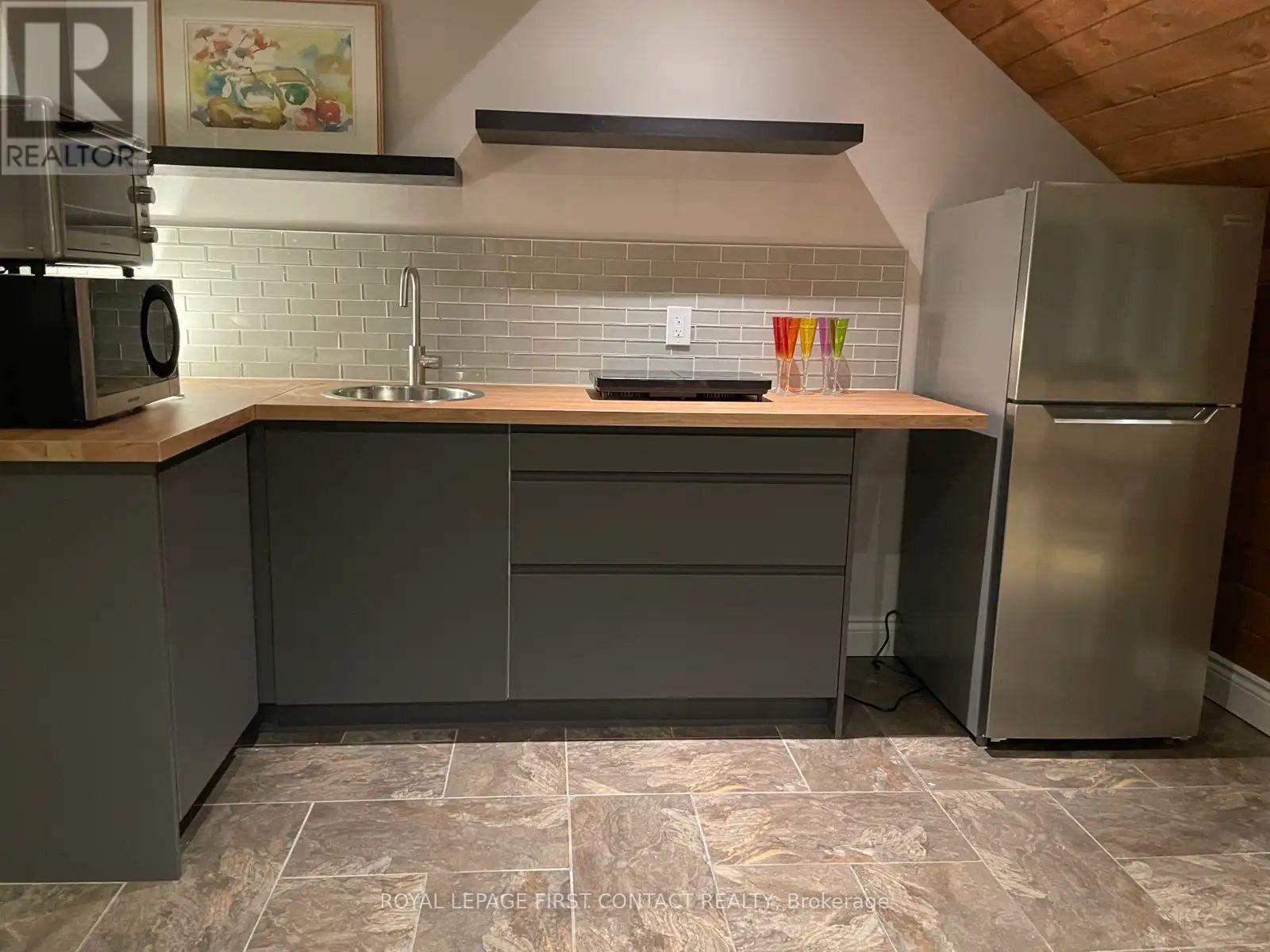 A kitchen with a refrigerator, sink, and cabinets.