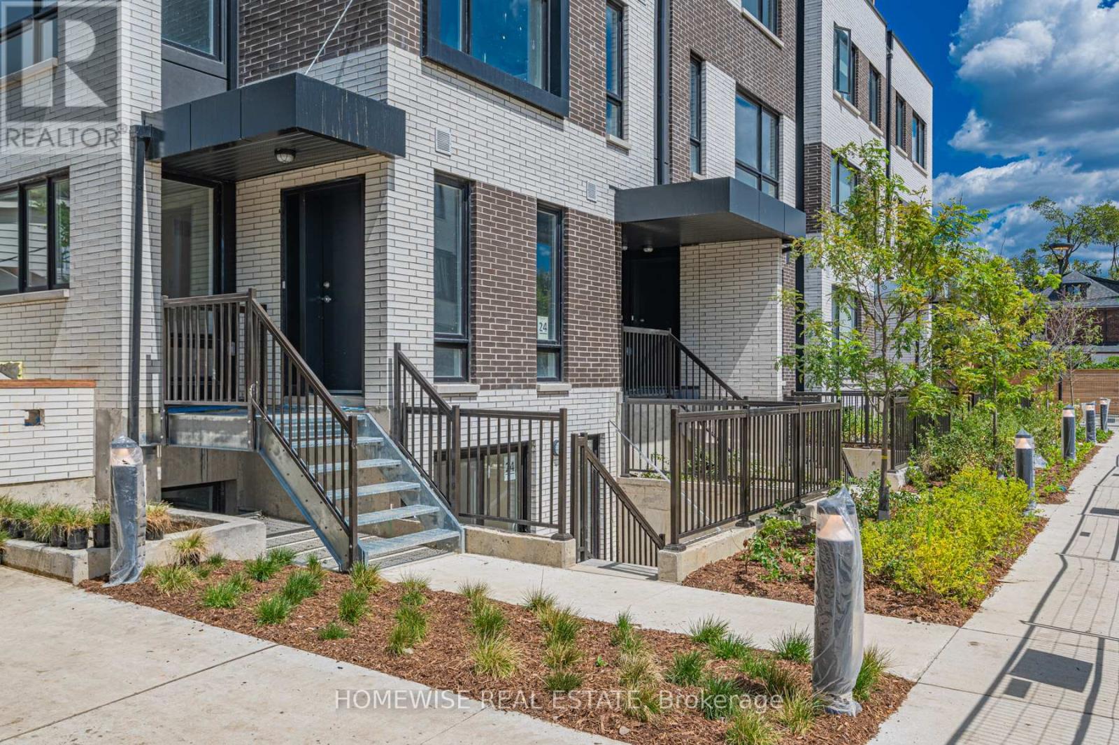 A modern brick apartment building with a well-maintained front yard.