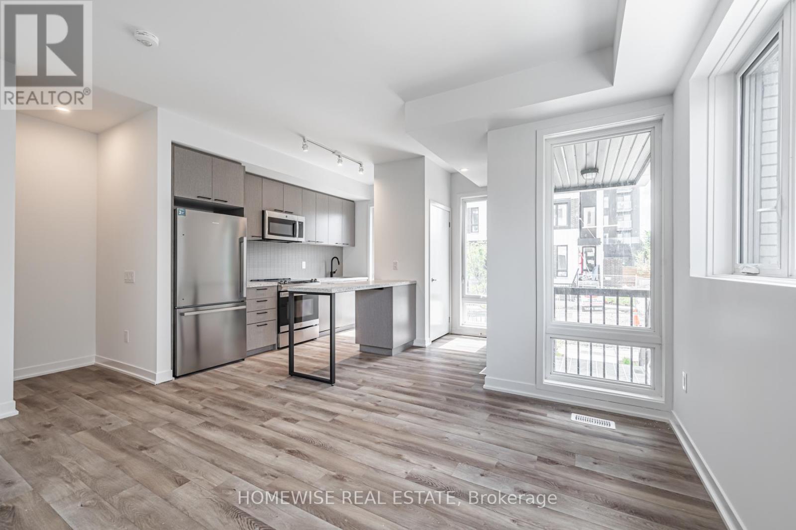 A spacious kitchen with a refrigerator, microwave, and a dining table with chairs.