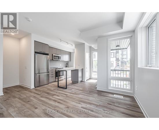 A spacious kitchen with a refrigerator, microwave, and a dining table with chairs.
