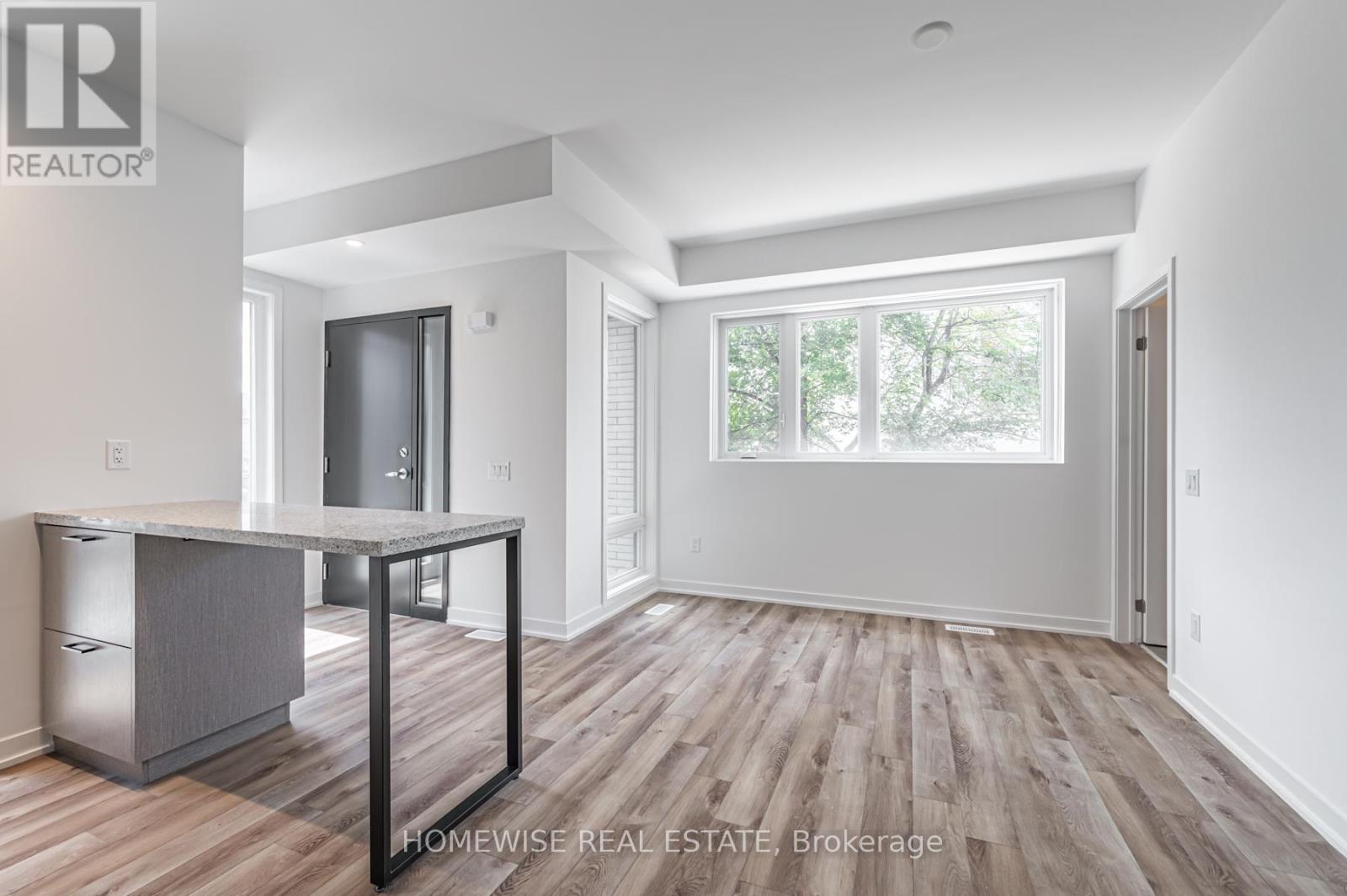 A spacious room with wood flooring and white walls.