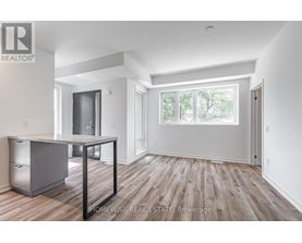 A spacious room with wood flooring and white walls.