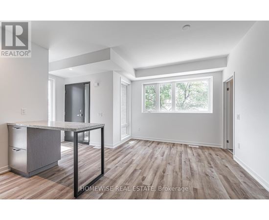 A spacious room with wood flooring and white walls.