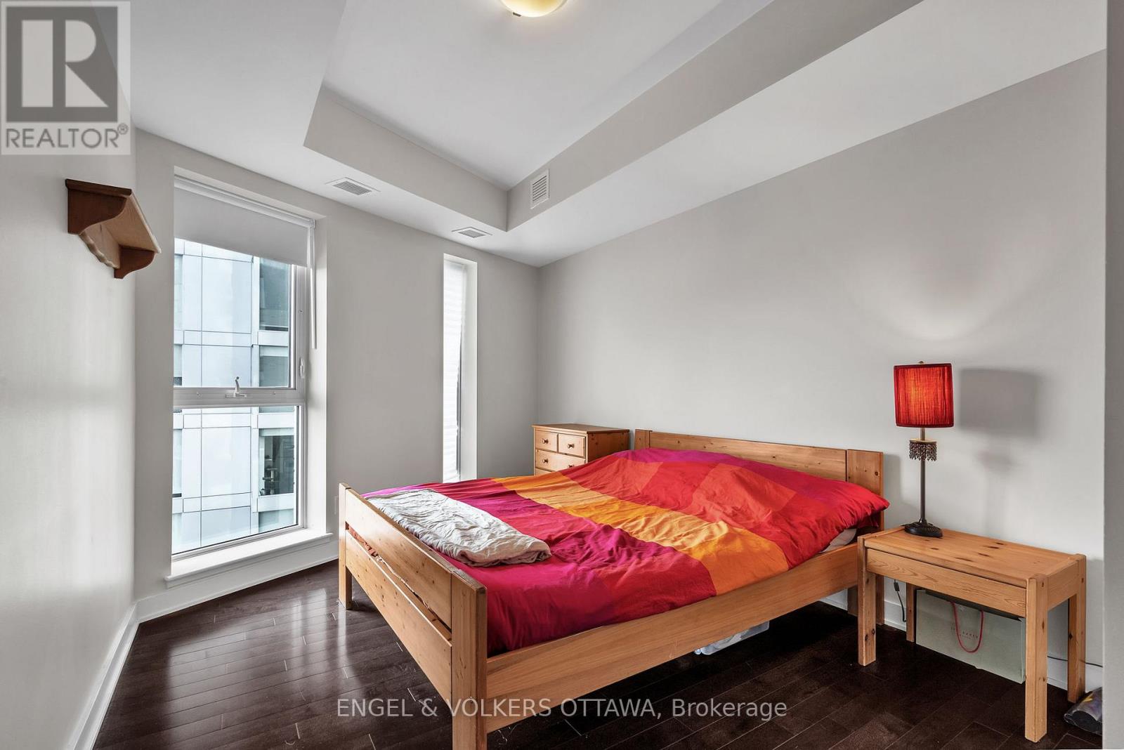 A bedroom with a bed, nightstand, and window.