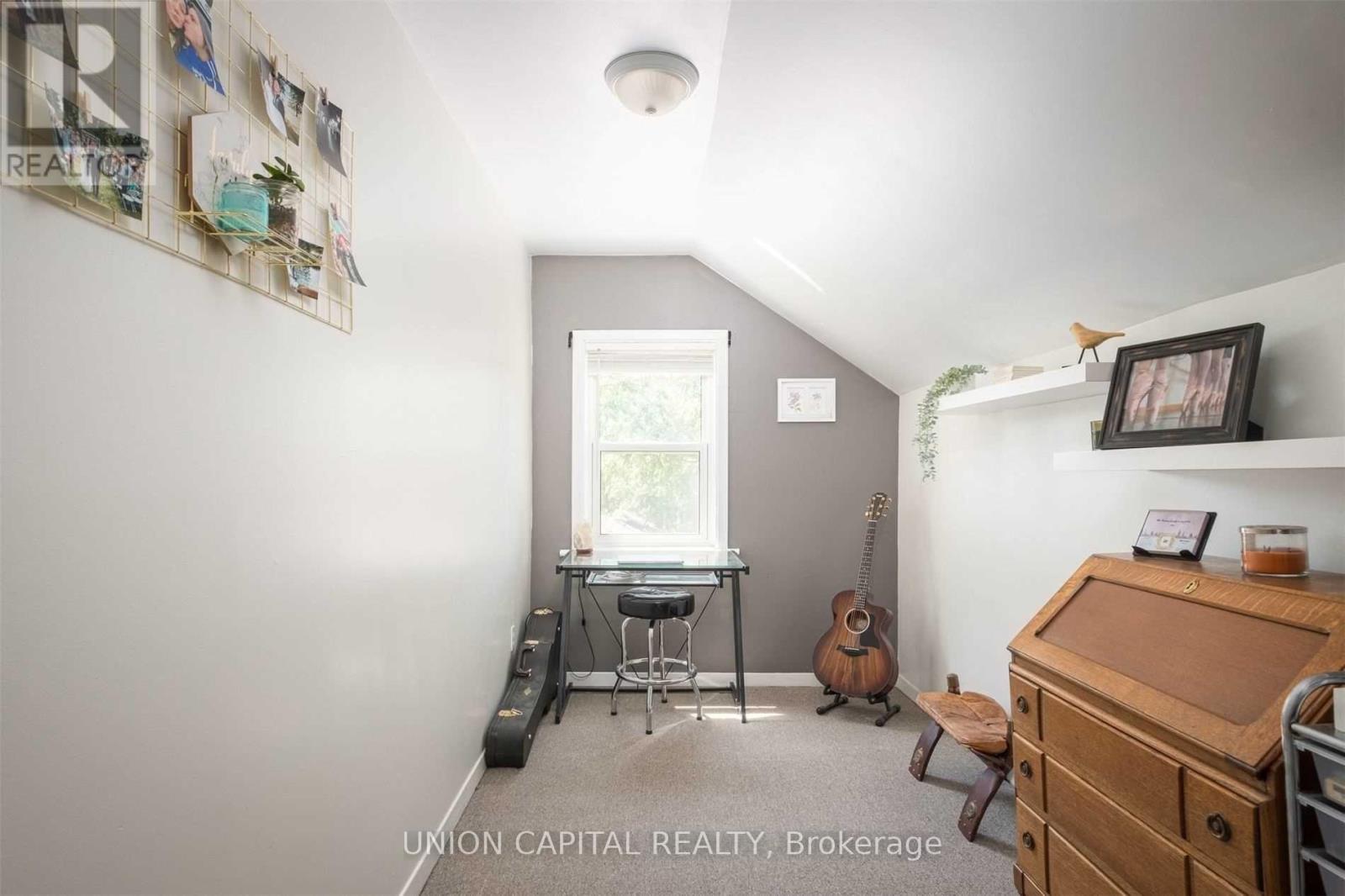 A room with a desk, chair, and guitar.