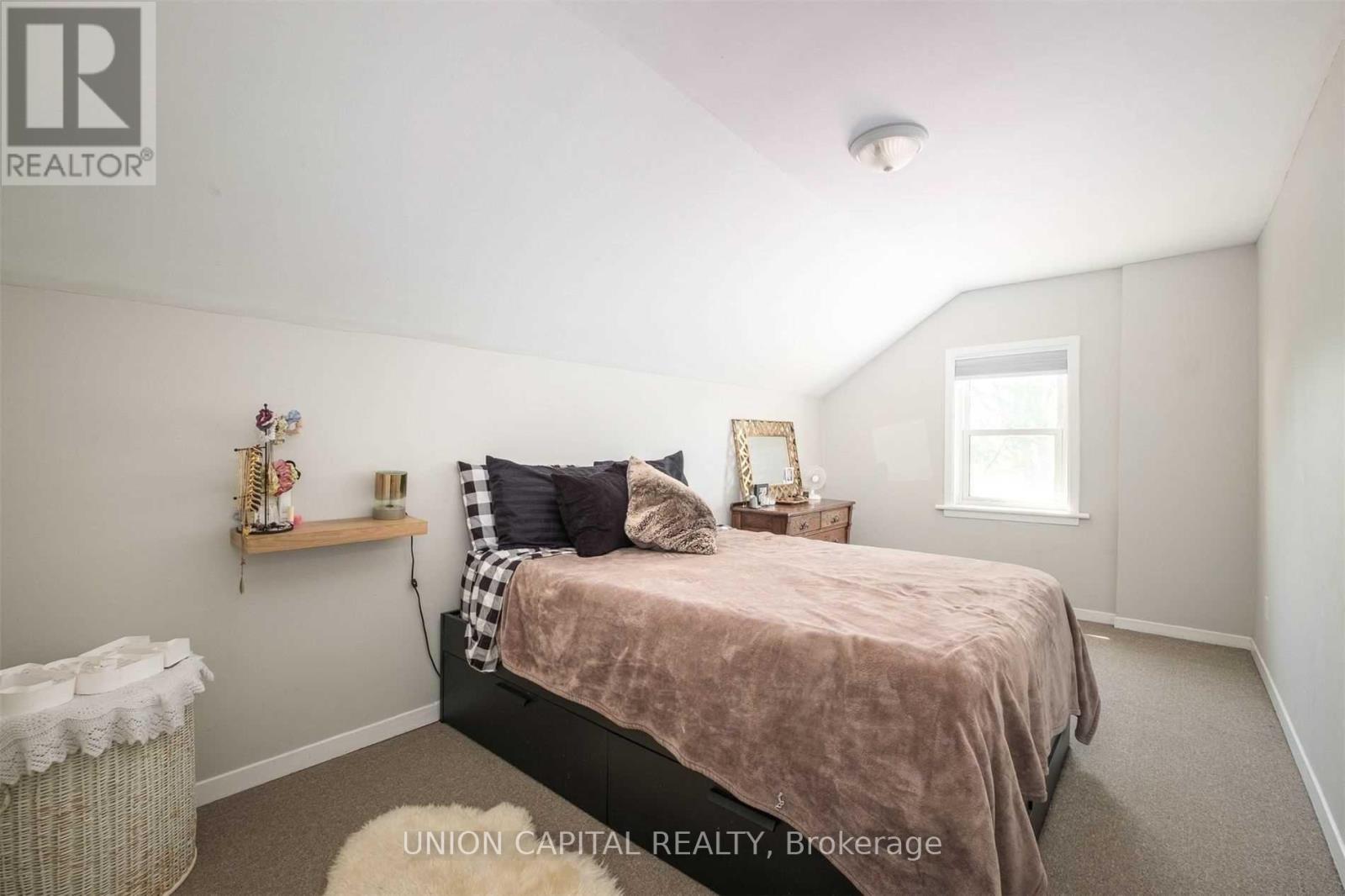 A bedroom with a bed, nightstand, and a window.