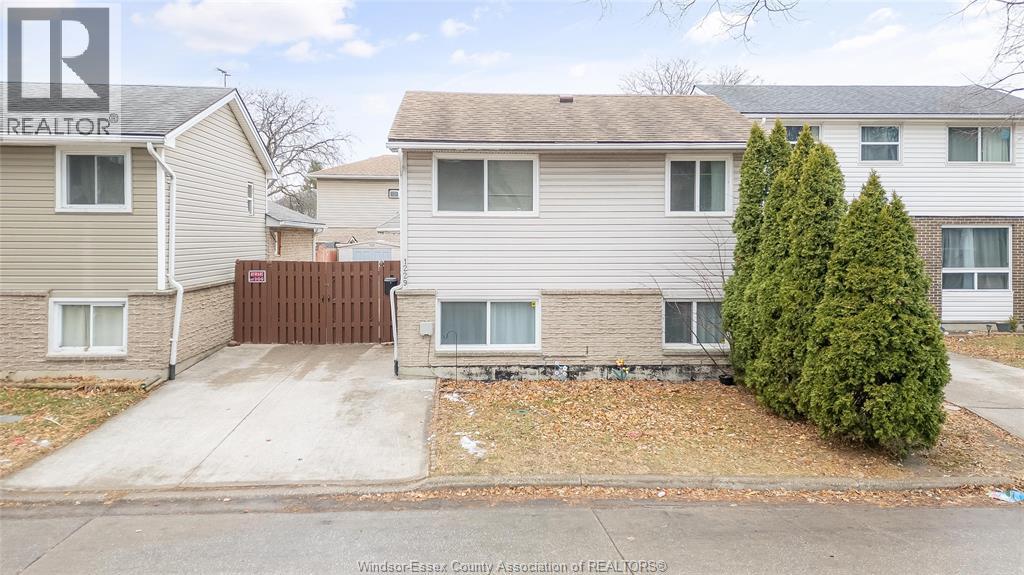 A house with a brown fence and a green tree in front.