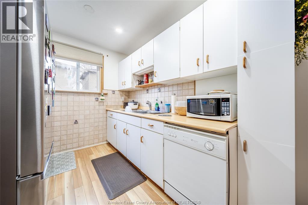 A kitchen with white cabinets and a wooden floor.