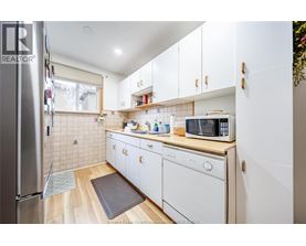 A kitchen with white cabinets and a wooden floor.