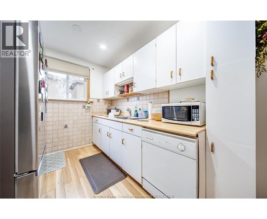 A kitchen with white cabinets and a wooden floor.
