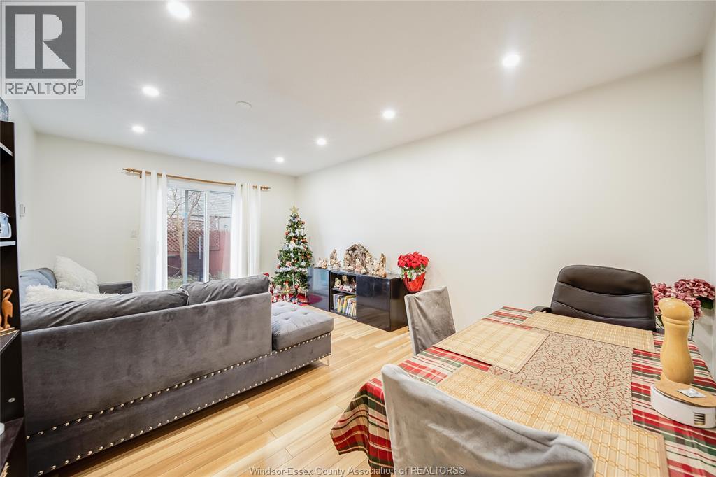 A bedroom with a grey couch, a bed with a patterned blanket, and a Christmas tree.