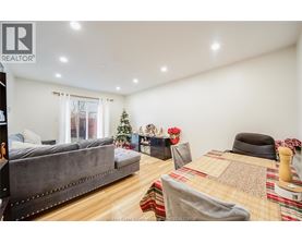 A bedroom with a grey couch, a bed with a patterned blanket, and a Christmas tree.