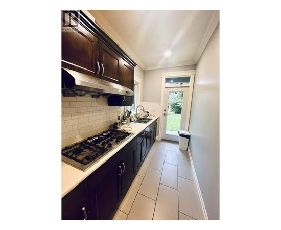 A kitchen with a stove top oven and dark brown cabinets.