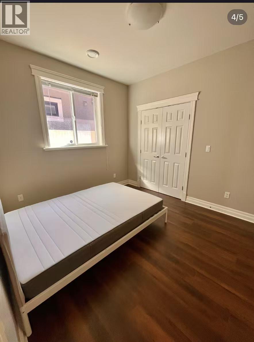 A bedroom with a bed, window, and door.