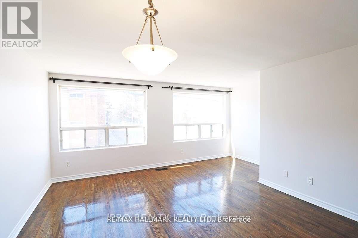 A room with a wooden floor and a large window with blinds.